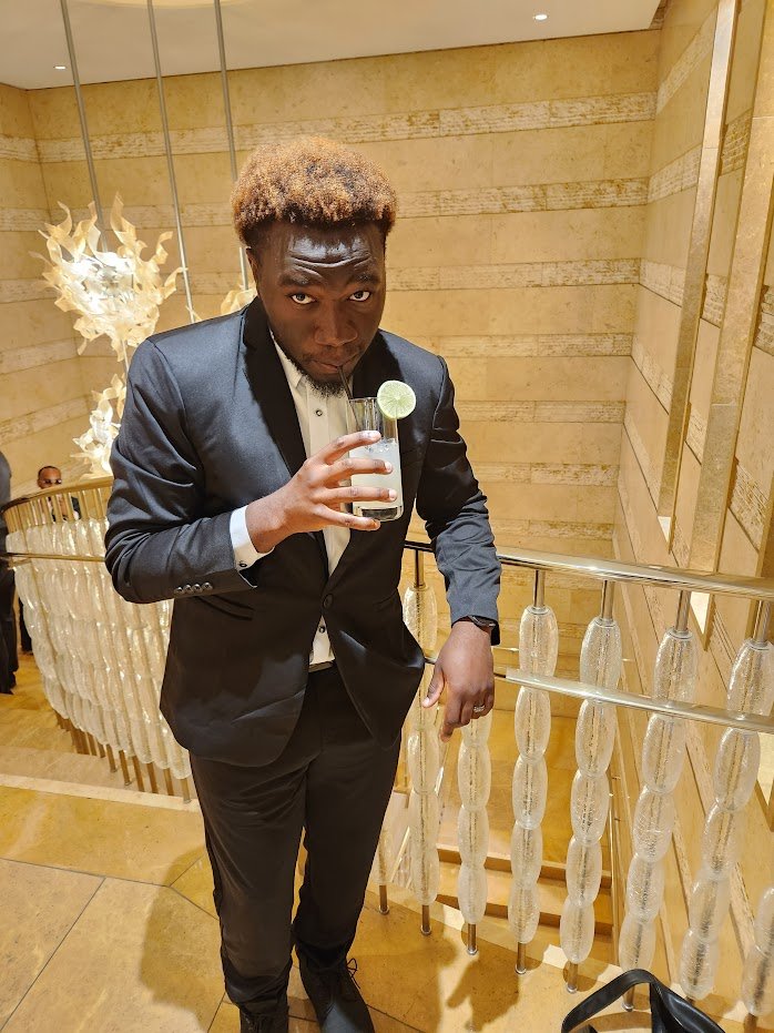 stuntyy in a black suit holding a drink
